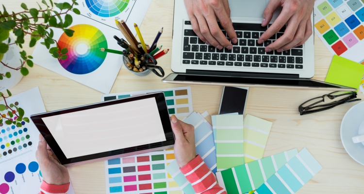 Hands of graphic designers using laptop and digital tablet in office